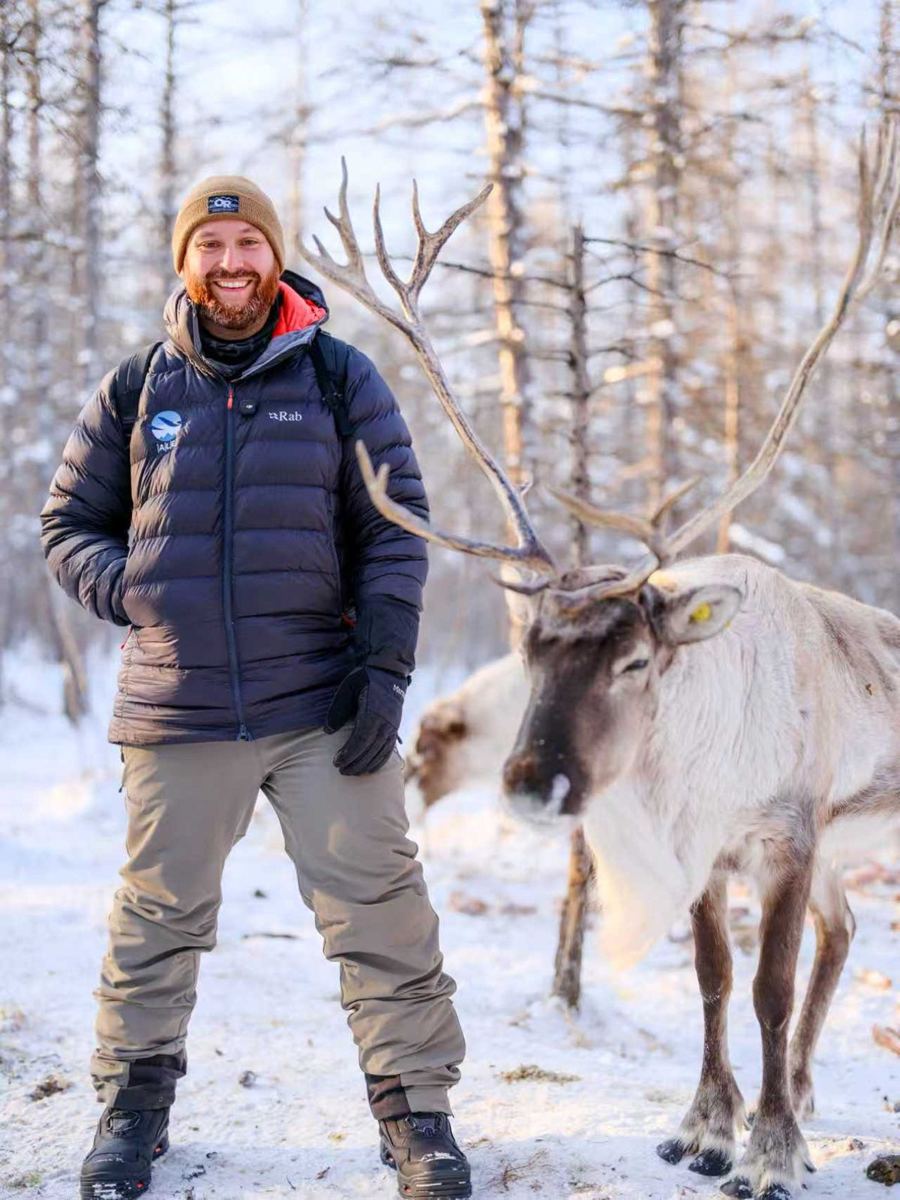 John, The Red Beard Explorer, standing next to a reindeer in the snow at Aoluguya