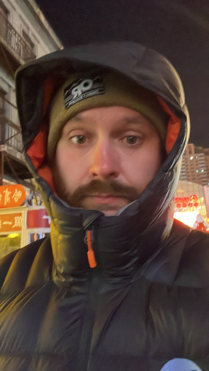 John bundled up in a hood and hat on a cold Harbin night