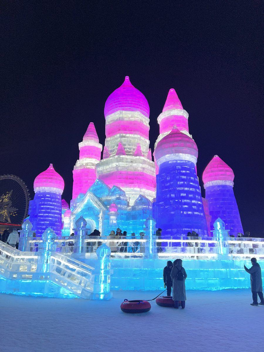The same kind of ice castles lit up pink and blue at night at Harbin Ice and Snow World